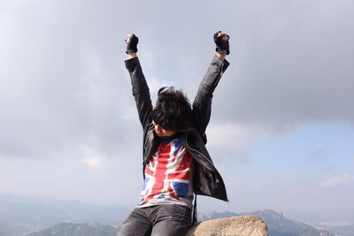 Low angle view of man with arms raised against sky