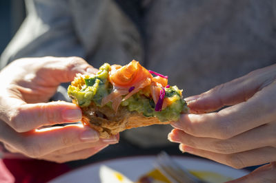 Eating salmon avocado sandwich. woman holds it in hand having lunch outdoors.