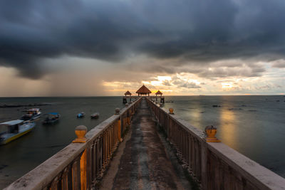 Pier over sea against sky during sunset