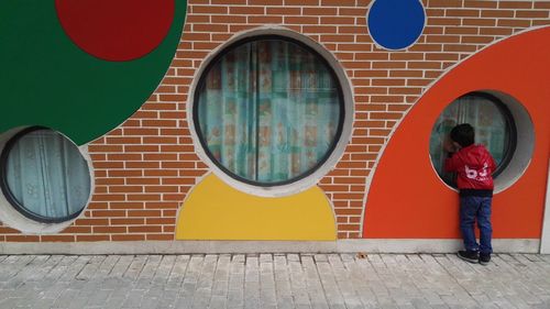 Rear view of boy looking through window