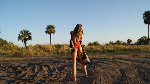 Rear view of young woman standing against clear sky