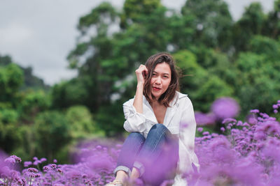 Portrait of woman sitting amidst purple flowering plants