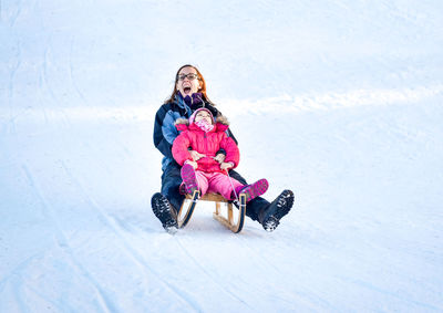 Full length of smiling girl sitting on snow