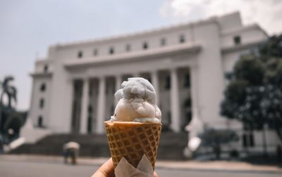 Hand holding ice cream against built structure