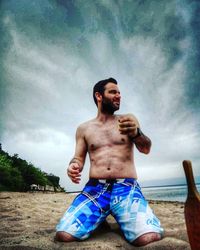 Full length of shirtless man lying on land against sky