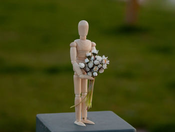 Close-up of figurine on wood against blurred background
