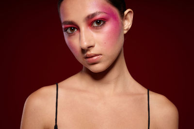 Portrait of young woman against black background