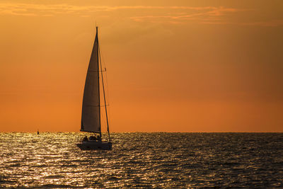 Sailboat sailing on sea against sky during sunset