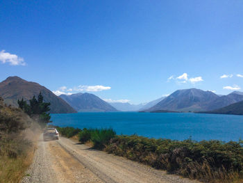 Scenic view of road by mountains against sky