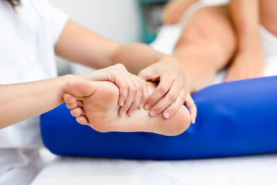 Midsection of woman massaging customer leg on bed