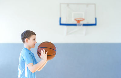 Side view of boy playing basketball