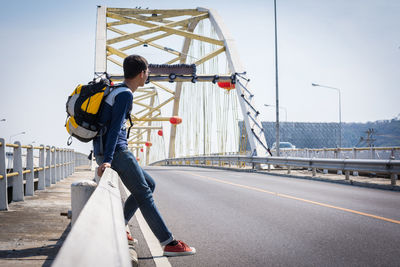 Rear view of man skateboarding on road against sky