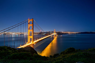 View of suspension bridge in city at night