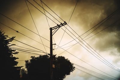 Low angle view of electricity pylon against cloudy sky