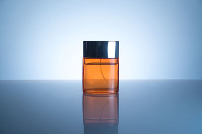 Close-up of perfume on table against blue background