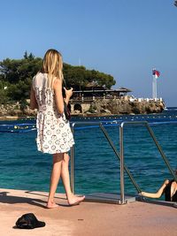 Rear view of woman on beach against clear sky