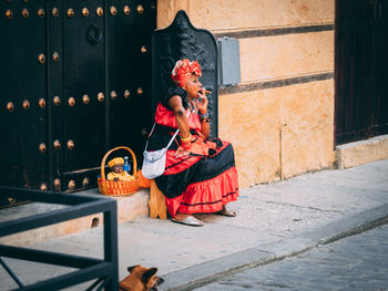 Full length of woman sitting on footpath