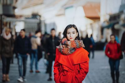 Portrait of confident young woman in warm clothing standing on city street