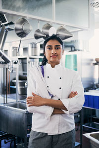 Portrait of female chef standing arms crossed in commercial kitchen
