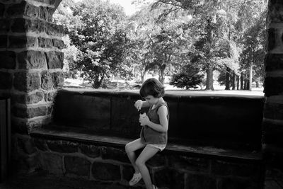 Girl on seat holding yogurt against trees