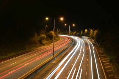 Road passing through illuminated city at night