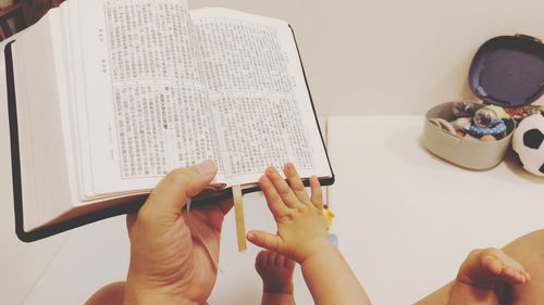 Midsection of woman reading book on table at home