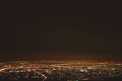 Illuminated cityscape against sky at night