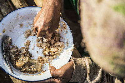 High angle view of woman eating rice and pork outdoors