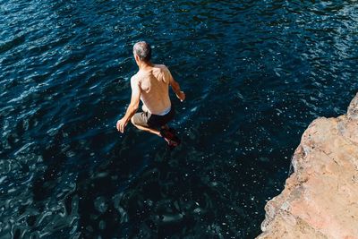 High angle view of man jumping into the sea