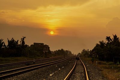 Railroad tracks against sky during sunset