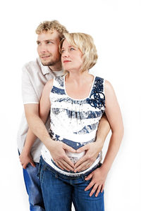 Portrait of young couple standing against white background