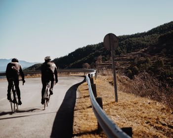 Rear view of people riding bicycle on road