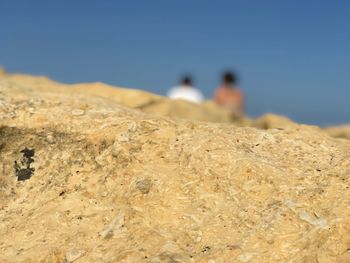 People on rocks against clear sky