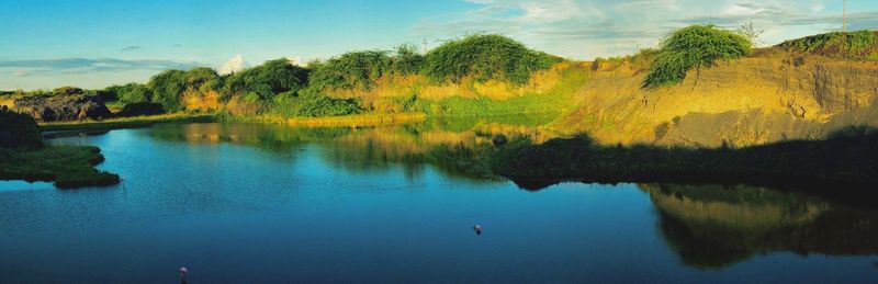 Scenic view of lake by trees against sky