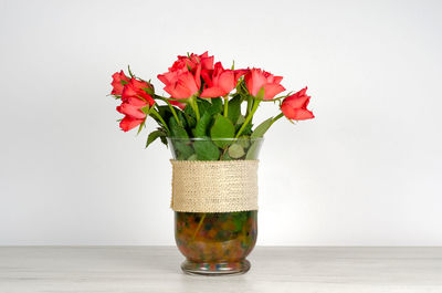 Close-up of red flower vase on table against white background