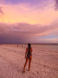 Full length of woman on beach against sky during sunset