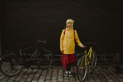 Young girl with bicycle standing on street