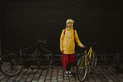 Full length of young man with bicycle standing on street