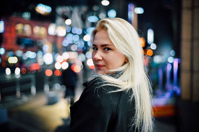 Portrait of woman in illuminated city at night