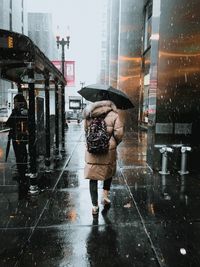 Woman walking on wet street during rainy season