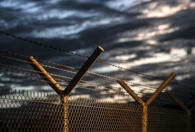 Close-up of barbed wire fence against sky