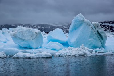 Ice floating on water against sky during winter