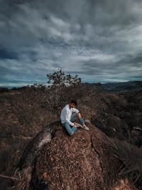 Man climbing rock on mountain against sky