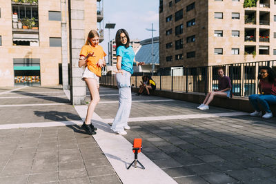 Girls dancing filming through smart phone on sunny day