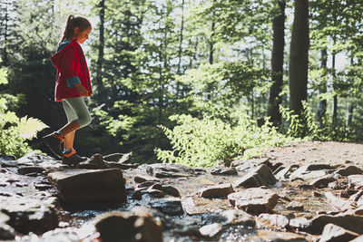 Child crossing mountain stream. little girl walking in mountains, spending summer vacations