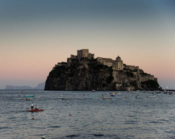 Building on island against clear sky during sunset