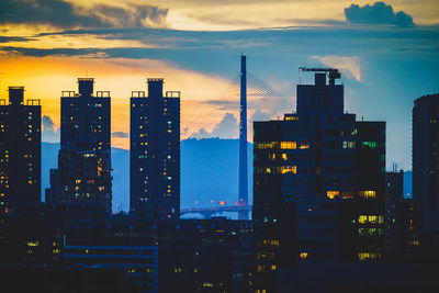 Illuminated modern buildings against sky during sunset