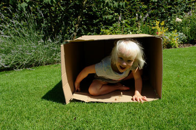 Portrait of girl sitting in box at back yard