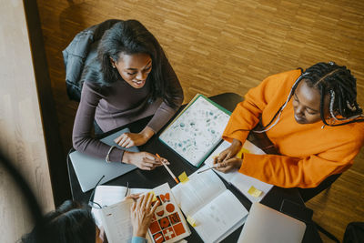 High angle view of smiling female students studying together at community college cafeteria