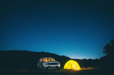 Car against illuminated blue sky at night